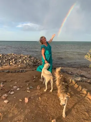 a woman standing on the beach with two dogs and a rainbow at Coral Paradise Villa in Safaga