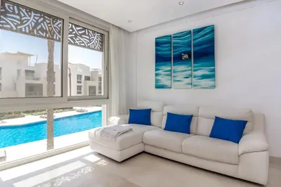 a living room with a white couch and blue pillows at Ollystays Mangroovy Seaview 1BR Beach and Pool Free access in Hurghada