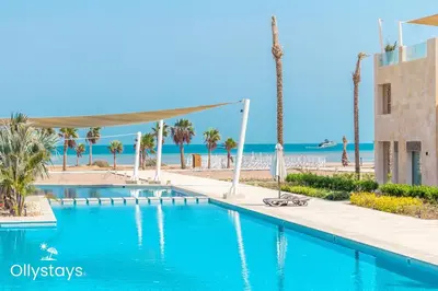 a swimming pool with the beach in the background at Ollystays Mangroovy Seaview 1BR Beach and Pool Free access in Hurghada