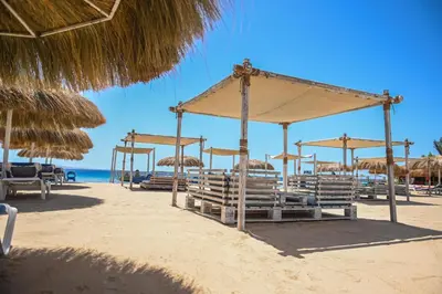 a beach with chairs and umbrellas and the ocean at AJIRA Boutique Hotel Hurghada Marina in Hurghada