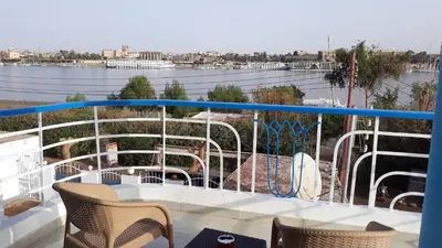 a balcony with a table and chairs on a boat at Hofni Palace Nile Niew in Luxor
