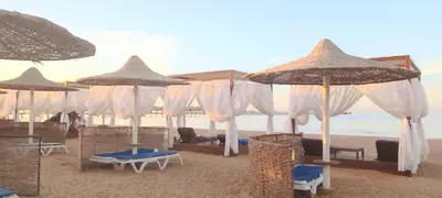 a beach with chairs and umbrellas on the sand at Chalet at Stella Makadi Beach in Hurghada