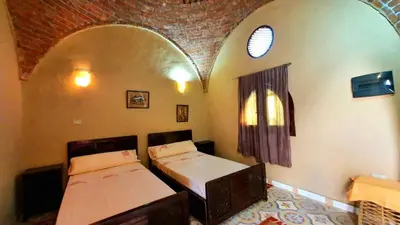 a bedroom with two beds in a room with an arch at Scorpion House Luxor in Luxor