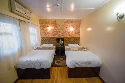 two beds in a small room with a window at Dahabiya ECO Queen Cleopatra in Esna