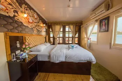 a bedroom with a large bed with a wooden headboard at Dahabiya ECO Queen Cleopatra in Esna