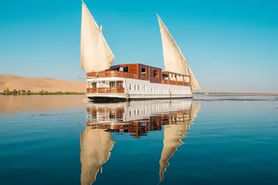 a boat on the water with its reflection in the water at Dahabiya ECO Queen Cleopatra in Esna