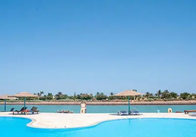 a swimming pool with chairs and umbrellas on a beach at El Gouna 1 bedroom apartment in West Golf Y12 in Hurghada