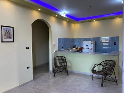 a kitchen with two chairs and a counter with purple lights at Elsanosy Family Guest House - Luxor in Luxor