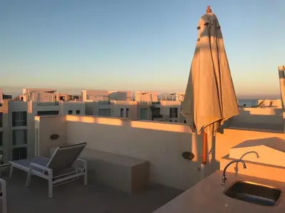 an umbrella and a chair on a balcony with a building at Jutta Deluxe 2-Bedroom-Apartment Mangroovy-M7 El Gouna in Hurghada