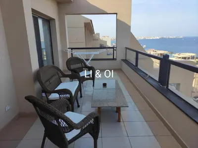 a balcony with chairs and a table and a view of the ocean at Full Apartment with Panoramic View of Hurghada in Hurghada