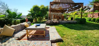 a garden with a couch and a table in the grass at Krouma Camp & Ecolodge in Aswan