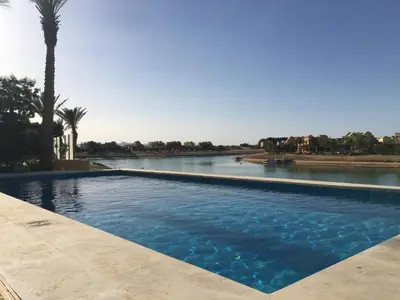 a swimming pool next to a river with a palm tree at Charming Lagoon Villa with pool Egyptian Style -Sabina 117 in Hurghada