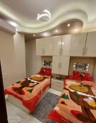two beds in a room with white cabinets at Rony's Ocean View Family Apartment in Hurghada