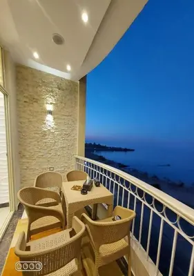a balcony with a table and chairs and the ocean at Rony's Ocean View Family Apartment in Hurghada