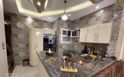 a kitchen with a marble counter top and white cabinets at Rony's Ocean View Family Apartment in Hurghada