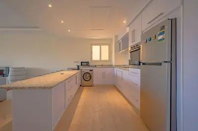 a kitchen with white cabinets and a washer and dryer at VESTA - Soma Bay Residence in Hurghada