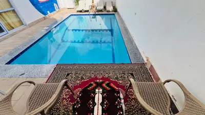 a table with two chairs next to a swimming pool at Tara Apartments in Luxor
