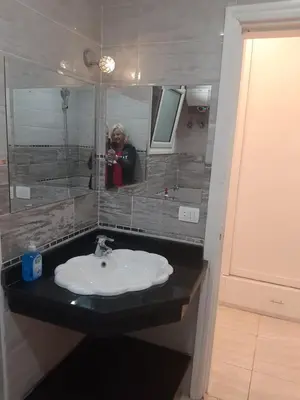 a woman taking a picture of a sink in a bathroom at apartman Marek in Hurghada