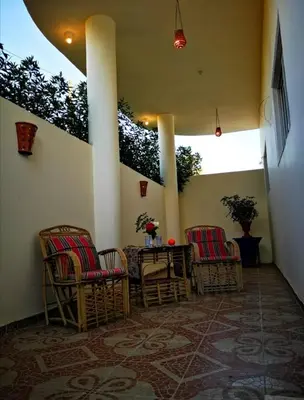 a porch with chairs and a table with flowers on it at Sinderella Private Pool Villa in Luxor
