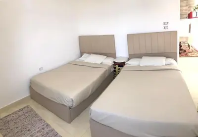 two beds in a room with white walls at Shipa Nubian Guest House in Aswan