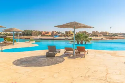 a swimming pool with chairs and umbrellas next to a pool at Sabina Classy 1 BR Apartment Lagoon view & Pool El Gouna in Hurghada