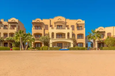 a large building with palm trees in front of it at Sabina Classy 1 BR Apartment Lagoon view & Pool El Gouna in Hurghada