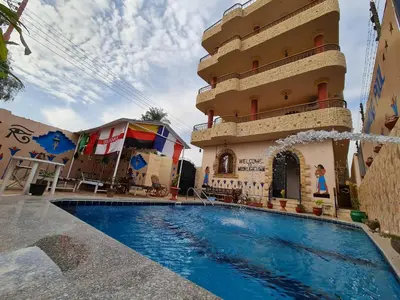 a building with a swimming pool in front of a building at Moonlight Home in Luxor