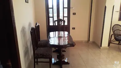 a wooden table and chairs in a room with a door at Moonlight Home in Luxor
