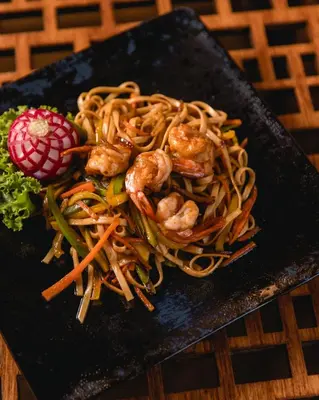a black plate of food with shrimp and noodles at The Grand Resort in Hurghada