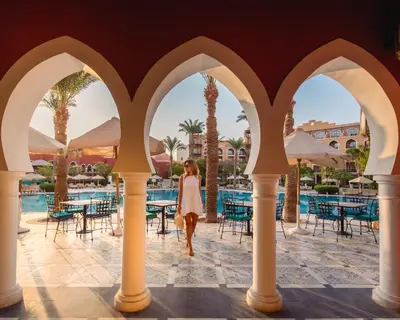 a woman walking through the arches of a pool at a resort at The Grand Resort in Hurghada