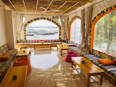 a room with tables and benches and a large window at Wanas Kato Guest House in Shellal