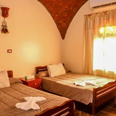 a bedroom with two beds and a window with towels at Wanas Kato Guest House in Shellal