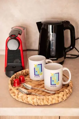 two coffee cups on a tray next to a coffee pot at Earthy & Tranquil 1 BDR Mangroovy Free Pool & Beach Access in Hurghada
