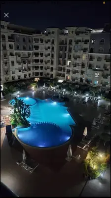 a large swimming pool in front of a building at night at florenza khamsin studio in hurghada pool view in Hurghada