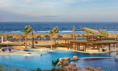 a resort with two pools and umbrellas and the ocean at Lazuli Hotel, Marsa Alam in Quseir