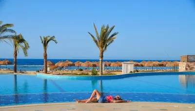 a woman laying on the edge of a swimming pool at a resort at Lazuli Hotel, Marsa Alam in Quseir