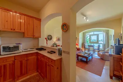 a kitchen with wooden cabinets and a living room at VESTA - El Gouna Residence in Hurghada