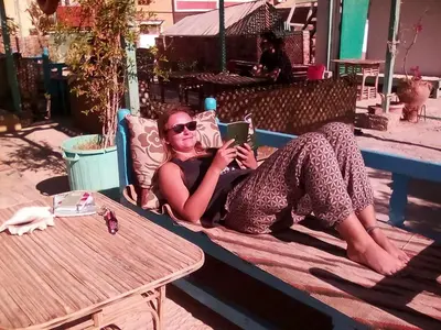 a woman laying on a bed looking at a tablet at Sea Waves Hostel not for Egyptian in Hurghada