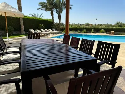 a black table and chairs next to a swimming pool at Villa with 5 bedrooms & 4 bathrooms - private heated pool in Hurghada