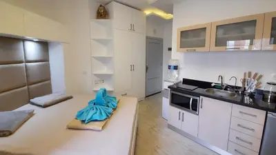 a kitchen with white cabinets and a blue towel on a couch at Aqua Palms Studio A210 in Hurghada