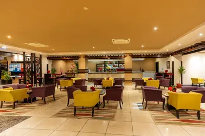 a hotel lobby with yellow chairs and tables at El Karma Beach Resort & Aqua Park - Hurghada in Hurghada