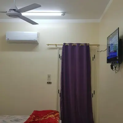 a room with a ceiling fan and a curtain at Sweet Home 5 Open 24 Hour in Hurghada