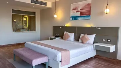 a bedroom with a large white bed and a pink bench at Sataya Resort Marsa Alam in Marsa Alam City