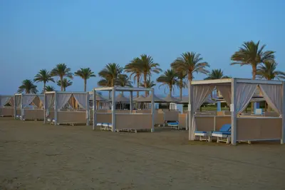 a row of tents on the beach with palm trees at Sataya Resort Marsa Alam in Marsa Alam City