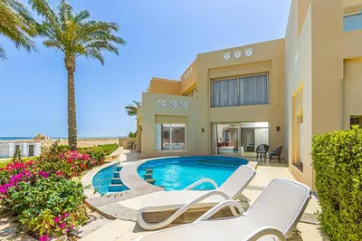 a villa with a swimming pool and palm trees at Sataya Resort Marsa Alam in Marsa Alam City