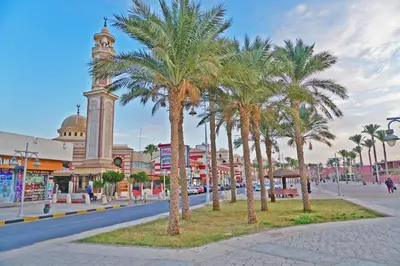 a city street with palm trees and a clock tower at The Touristic Promenade Apartment in Hurghada