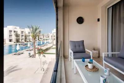 a balcony with a view of a pool and a chair at Epic & Exquisite 2 BR w Beach & Pool Mangroovy in Hurghada