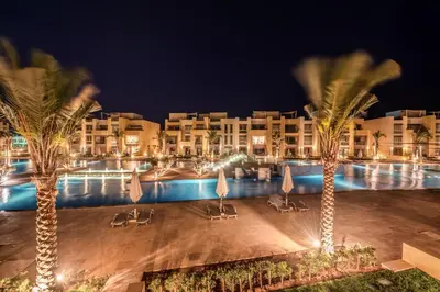 a resort with a pool and palm trees at night at Epic & Exquisite 2 BR w Beach & Pool Mangroovy in Hurghada