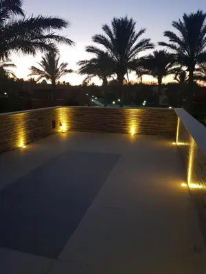 a wall with lights in front of palm trees at Chalet stella makadi family only in Hurghada