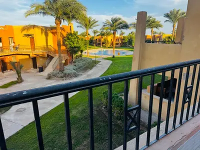 a resort balcony with palm trees and a pool at Chalet stella makadi family only in Hurghada